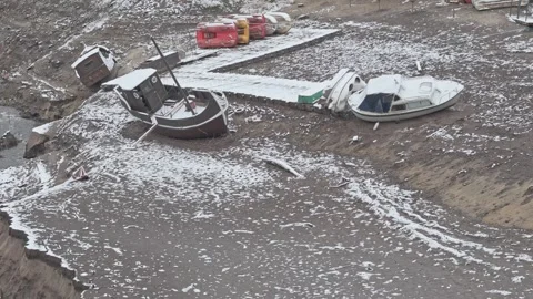 Drone view of a dried lakebed with snow-covered ground and stranded fishing.. Stock Footage 296756391