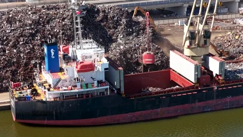 Drone View of Excavator Loading Scrap Metal onto Cargo Ship at Industrial Dock Stock Footage 344989016