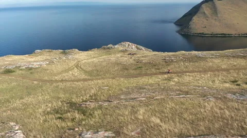 Drone view of Extreme Pro Motocross Biker riding on rock area at sea shore Stock Footage 269791107
