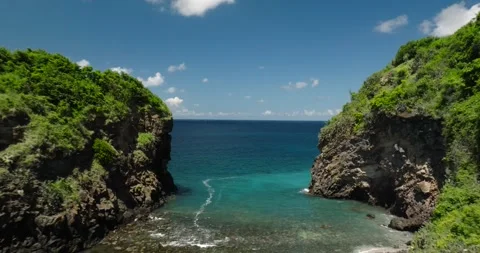 Drone view flying between rocks and cliffs over the ocean to the horizon Stock Footage 276253986