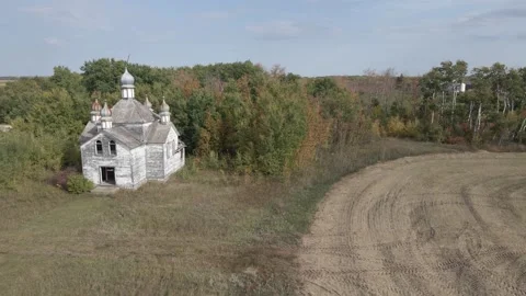 Drone view flying over abandoned dilapidated white Ukrainian church surrounded Stock Footage 330363820