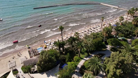 Drone view flying over a sunny beach resort with tourists swimming and relaxing Video stock 333459559