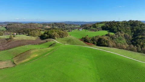 Drone view flying over a vast rural landscape with green meadows, rolling Stock Footage 319645165