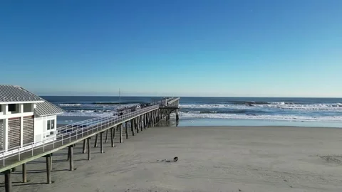Drone view flying parallel to a wooden pier following a person walk towards.. 스톡 동영상 225770669