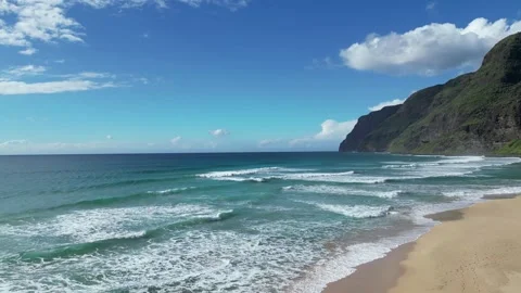 Drone view of footprints on a sandy beach below green cliffs in Hawaii Stockbeeldmateriaal 348263754