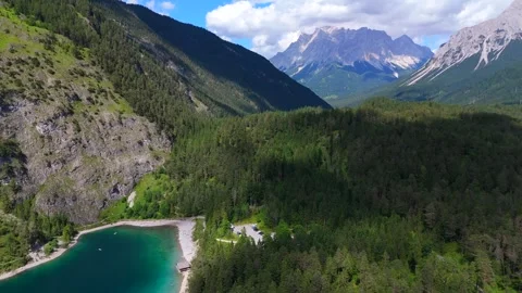 Drone view of forested mountain valley with rocky peaks and turquoise lake shore 스톡 동영상 314893843
