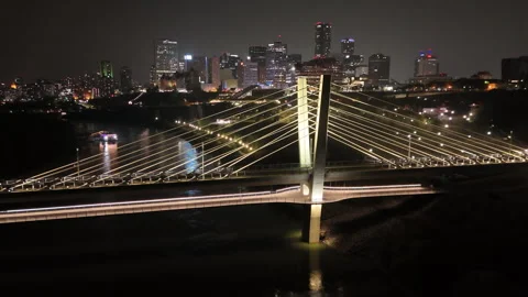 Drone view of glowing bridge and riverfront city lights at night Stock Footage 316178041