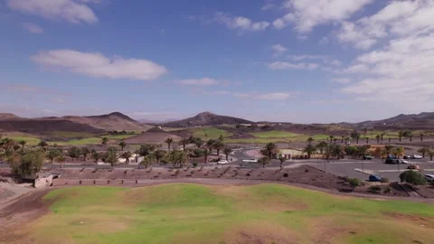 Drone View of Golf Course and Palm-Lined Road with Mountains in Fuerteventura Stock Footage 309014047