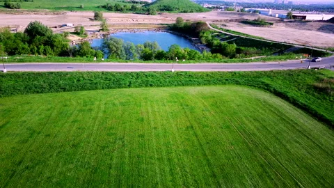 Drone View of Green Parkland, Road, and Pond near an Industrial Zone Vídeo Stock 347151653