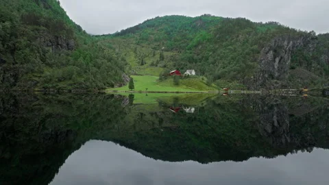 Drone view of a green valley and Norwegian houses reflected in a calm lake. Stock Footage 328132267
