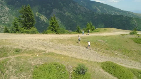 Drone view of group of hikers reaching the top of a hill with forested mountains Stock Footage 157906766