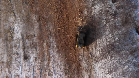 Drone view of heavy machinery clearing land near roadside. A bulldozer removes Stock Footage 324263534