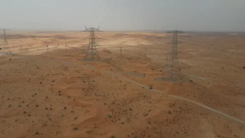 A drone view of High-voltage electric poles in the desert in UAE Stock Footage 333470454
