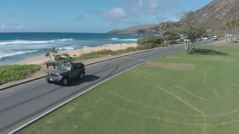 Drone View Of Jeep Wrangler Driving At Sandy Beach Park In Honolulu, Hawaii Stock Footage 154172039
