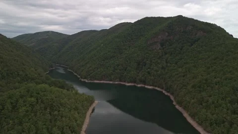 Drone view of Lake Tarnița, forested hills and calm water reflections below Stockbeeldmateriaal 339770650