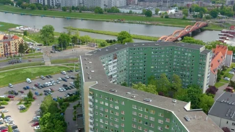 Drone view of large green apartment complex by river with red bridge Stock Footage 308939959