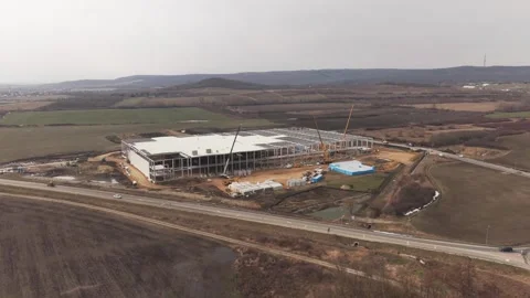 Drone view of a large industrial warehouse under construction surrounded by Видео 331612824