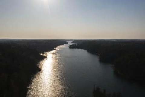 Drone view of large river with reflections of sun and forest Stock Photos