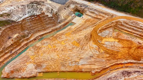 Drone view of layered sand quarry walls with teal water channel, Bulgaria Stock Footage 336725405