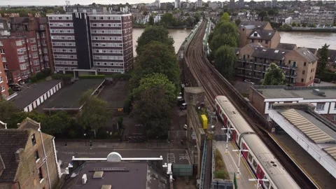 Drone view of a London Underground train pulling into the Fulham Railway Bridge Stock Footage 191939661