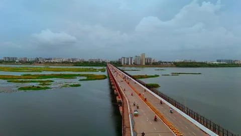Drone View of Long Bridge Crossing Wide River with Urban Skyline in Background Stock-Fotos