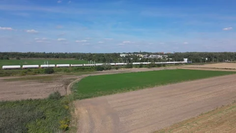 Drone view of long freight train traveling through rural landscape. Video stock 315535520