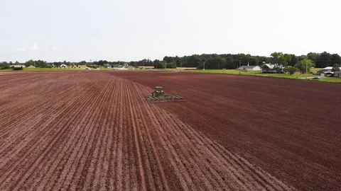 Drone view looking along straight lines produced by tractor in field in Stock Footage 109475672