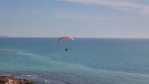 Drone view of a man Paragliding over the sea on a sunny bright day with blue sky Stock Footage 264819191