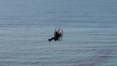 Drone view of a man Paragliding over a seascape on a sunny bright day Stock Footage 264819202