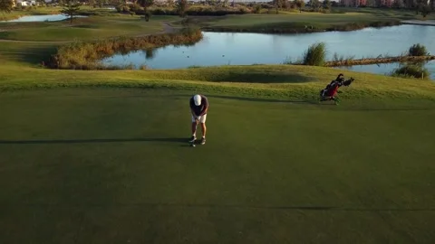 Drone view of a man playing golf on a large golf course next to a lake. Video stock 252603864