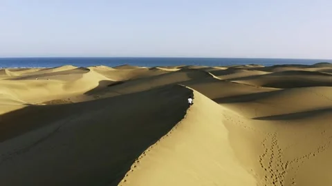 Drone view of a man running on sand dunes in Maspalomas, Gran Canaria Stock Footage 243195033