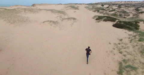 Drone view of man sprinting for help on sandy dunes in Santa Cruz Stock Footage 148492901