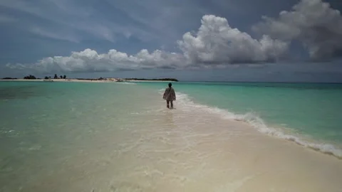Drone view of a man walking away from the camera across a pristine white Vidéo 345932655