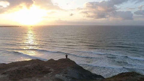 Drone view of man watching sunset from the cliffs in Peniche, Portugal Stock Footage 126352364