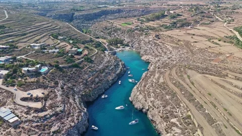 Drone view of Mġarr ix-Xini bay, Gozo, with boats, blue water and cliffs Stock Footage 341712022