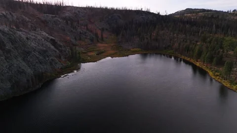A drone view of a mountain lake with rocky cliffs and dynamic light Stock Footage 296920177
