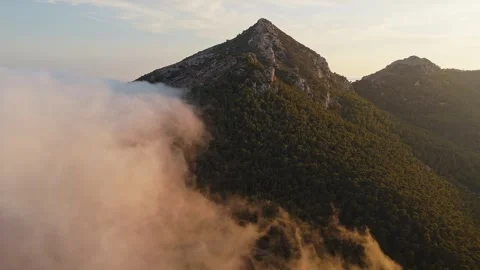 Drone view of mountain peak with forest and clouds at sunset Stock Footage 314605389