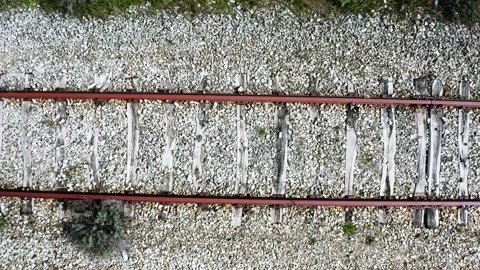 Drone view moving over old rusty train tracks with weathered wooden sleepers Stock Footage 337692231