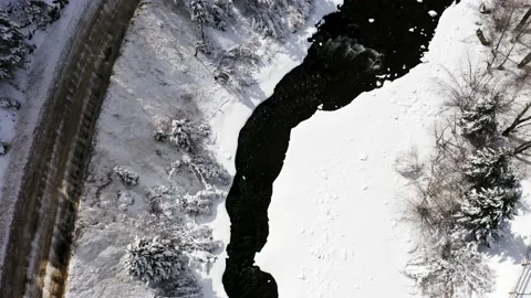 Drone view of narrow Clear Creek river flowing through snowy forest in daylight Stock Footage 149536226