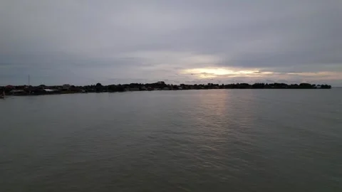 Drone view from ocean to land, seeing the silhouette of the village Stock Footage 258321700