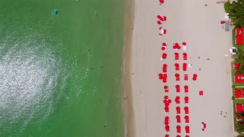 Drone view on ocean shore and sandy beachfront with many deck chairs and red sun Stock Footage 245998929