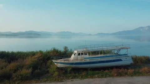 Drone view of old abandoned pleasure or fishing boat on shore of lake Stock Footage 252590736