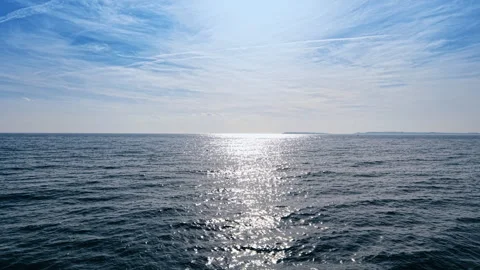 Drone view of open sea with sunlight glinting on the surface and cirrus clouds Stock Footage 335518111