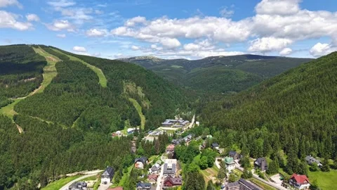 Drone view over alpine valley village surrounded by dense forest, winding roads, Vídeo Stock 342355330