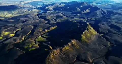 Drone view over Iceland’s dark volcanic plains and jagged moss-covered ridges Stock Footage 323436789