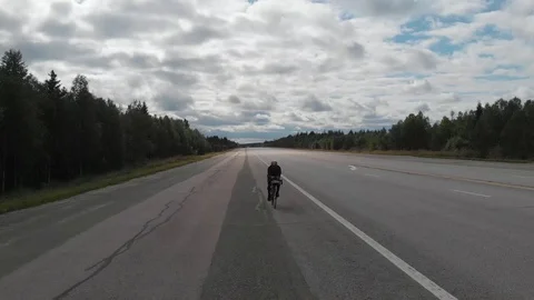 Drone view over a large asphalt road and a cyclist on it Stock Footage 114386857