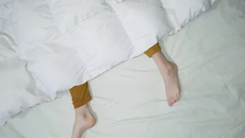 Drone view over womans legs in orange pajama pants under the white blanket Stock Footage 161012174