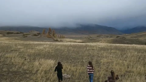 Drone view over young female travelers running through grassy steppe Stock Footage 156967271