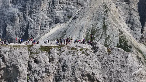 Drone view of a peak of dolomites with many people and a cross Stock Footage 263267168