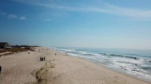 Drone view of people walking on beach with waves crashing Видео 106098660